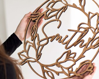 May include: A wooden wall decor with a floral design and the name "Smith" cut out in the center.