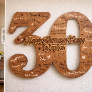 Op de afbeelding: Houten verjaardagsdecoratie in de vorm van het cijfer 30, met de tekst "Happy Birthday Clara" en de datum 21/03/26. Het cijfer is versierd met hartjes en verjaardagswensen in witte letters.