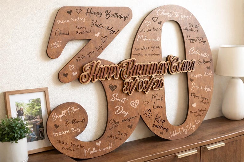 Op de afbeelding: Een houten verjaardagsdecoratie in de vorm van het getal 30. De cijfers zijn bruin met gegraveerde tekst en hartjes. De woorden "Happy Birthday Clara" en de datum staan in het midden.