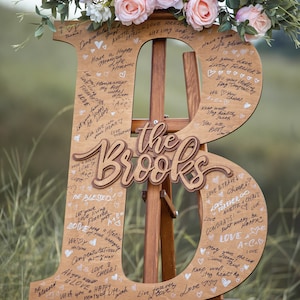 Pu&ograve; includere: Un cartello di legno a forma delle lettere "B" ed "R" con le parole "The Brooks" in mezzo. Il cartello &egrave; decorato con fiori e ha molti messaggi scritti a mano.