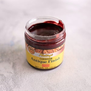 May include: A small jar of Fiebing's Cordovan Antique Finish leather dye. The jar is yellow with black text and a red lid. The dye is a dark red color.