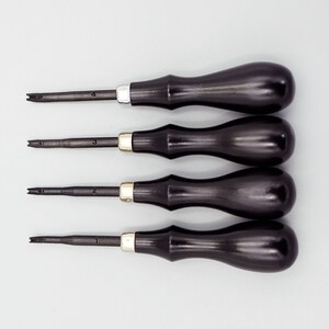 May include: Set of four black handled tools with metal tips, numbered 1 through 4. The tools are used for leather crafting.