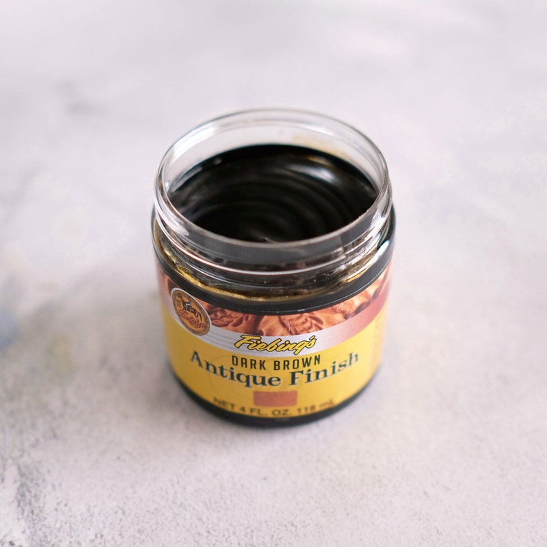 May include: A glass jar of Fiebing's Dark Brown Antique Finish leather dye. The jar is open and the dye is visible inside.