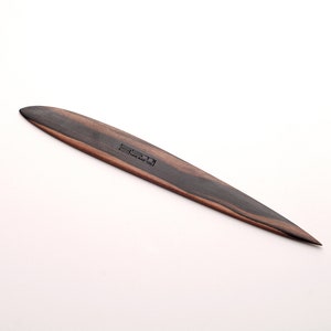 May include: A long, thin, black and brown wooden letter opener with a pointed tip. The letter opener has the text "Made in Italy" engraved on the side.