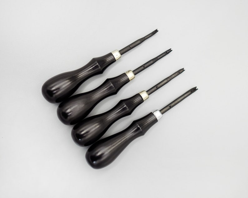 May include: Set of four black handled tools with silver accents. The tools have different sized blades and are used for leather crafting.