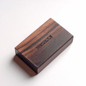 May include: A small wooden box with a dark wood grain finish. The box has a black engraved logo that reads "E3T1 HAND MADE TOOL".