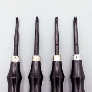 May include: Four black handled tools with different shaped tips, numbered 1 through 4. The tools are used for leather crafting.