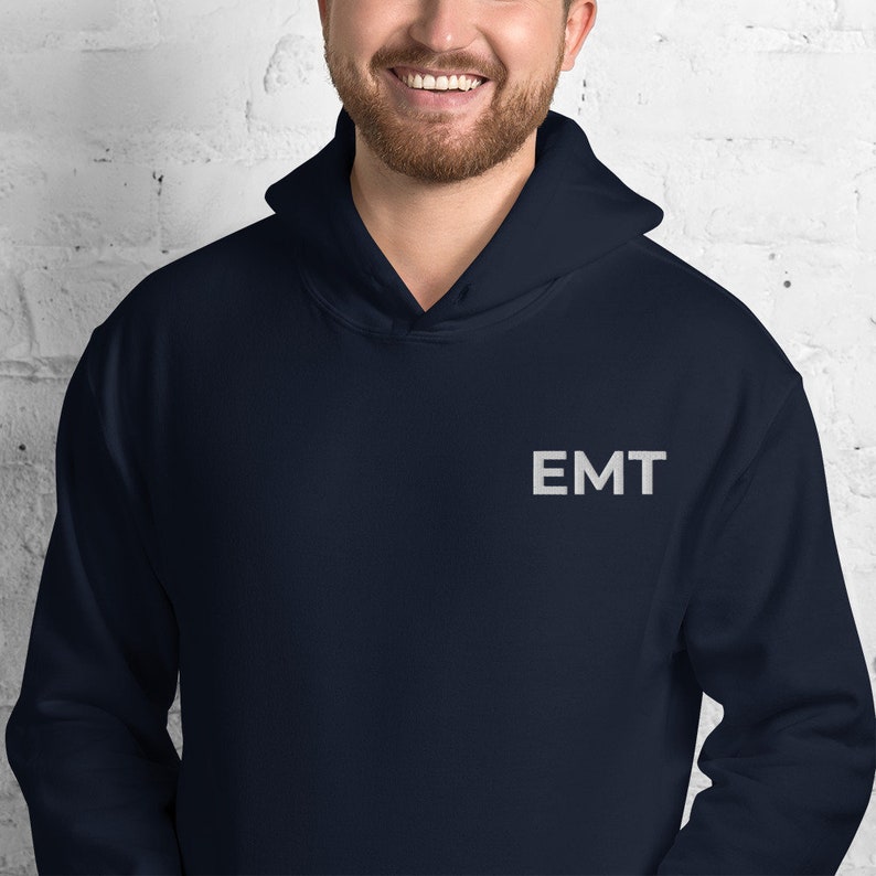 May include: A navy blue hoodie with the word "EMT" embroidered on the front in white.