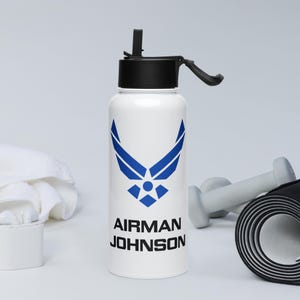 Może przedstawiać: Biała butelka na wodę z niebieskim logo Sił Powietrznych i tekstem "AIRMAN JOHNSON".