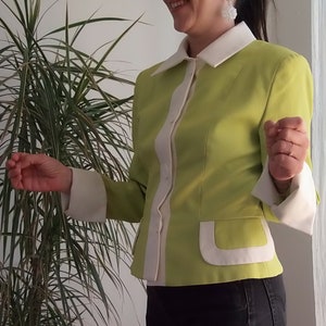 May include: A lime green blazer with white trim and pockets. The blazer has a white collar and buttons.