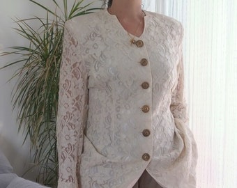 May include: A white lace jacket with gold buttons. The jacket has a long sleeve and a collar.
