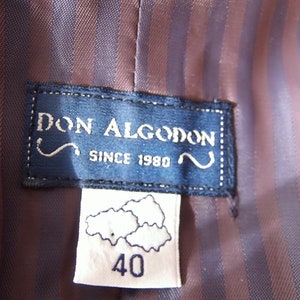以下が含まれることがあります： 「Don Algodon Since 1980」というテキストが書かれた青と白のラベルと、「40」というテキストとスタイリッシュな雲のデザインが書かれた白いラベルです。