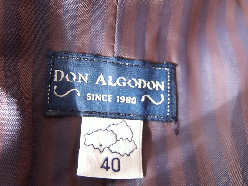 以下が含まれることがあります： 「Don Algodon Since 1980」というテキストが書かれた青と白のラベルと、「40」というテキストとスタイリッシュな雲のデザインが書かれた白いラベルです。