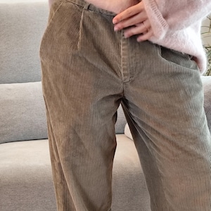 May include: A pair of light brown corduroy pants with a straight leg fit. The pants have a belt loop waistband and a zipper fly.