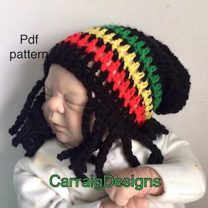 May include: A crochet baby hat in the style of a Rasta hat, featuring black, red, yellow, and green colors. The hat has long, black dreadlock-style strands. The words "Pdf pattern" and "CarraigDesigns" are visible in the image.