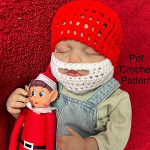 May include: A baby wearing a red crocheted Santa hat and a white crocheted beard. The baby is holding a red and white elf doll. The text "Pdf Crochet Pattern" is visible on the right side of the image.
