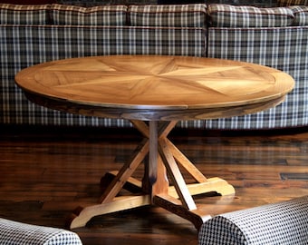 May include: A round wooden table with a starburst design on the top. The table has a pedestal base with four legs.
