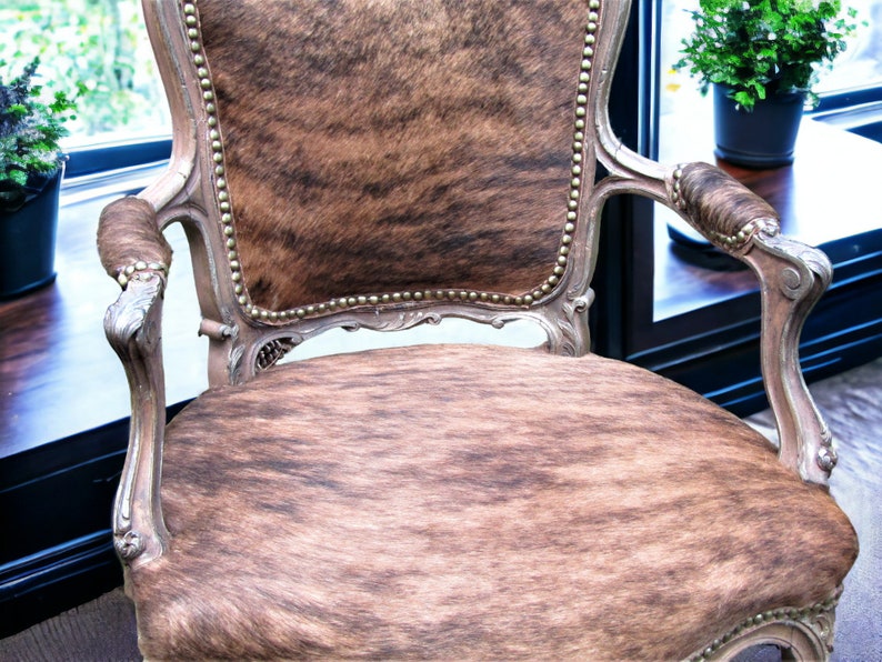 Pu&ograve; includere: Una poltrona in stile vintage con rivestimento in pelle di mucca marrone e bianca. La sedia ha una struttura in legno intagliato e dettagli decorativi.