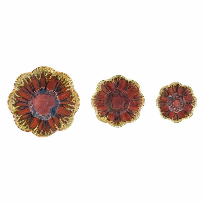 May include: Three decorative flower-shaped dishes. The dishes have a red center with a gold-colored rim and petal-like edges. The sizes vary, with the largest dish on the left and the smallest on the right.