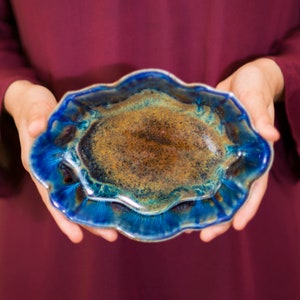 May include: A blue and brown ceramic dish with a wavy edge. The dish has a glossy finish and a unique pattern.