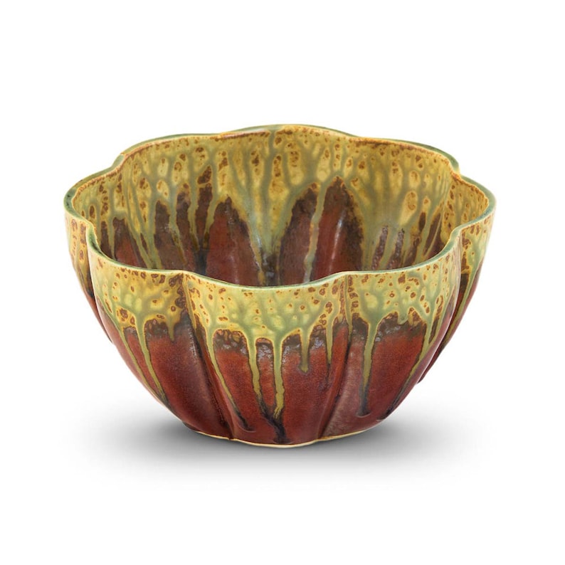 May include: A ceramic bowl with a unique, scalloped rim. The bowl features a rich, reddish-brown base with a textured, dripped glaze in shades of olive green and tan around the rim. The bowl's design is both functional and decorative.