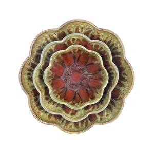 May include: Overhead view of three ceramic bowls stacked together. The bowls have a scalloped edge and a flower-like shape. The bowls have a brown and green color scheme, with a reddish-brown center and a green rim.
