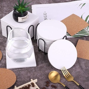 May include: A set of 10 white round coasters with a black metal stand. The coasters are stacked on top of each other and the stand is made of metal with a black finish. The coasters are made of a thick, durable material and are perfect for protecting your furniture from scratches and spills.