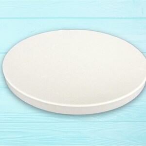 May include: A white round cake board, ideal for decorating cakes and pastries. The board is smooth and has a slightly textured surface.