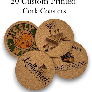 May include: Set of four cork coasters with different designs. The coasters feature a pig, a Cracker Barrel logo, a bear, and a Leatherneck logo. The coasters are round and have a natural cork finish.