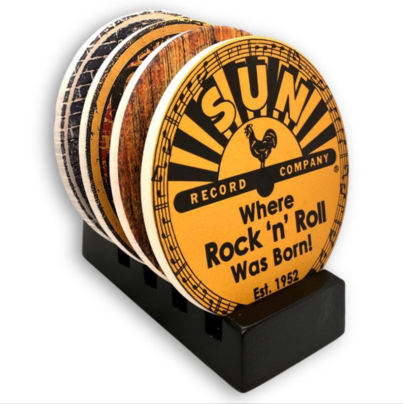 May include: A set of round coasters with a black holder. The coasters feature various designs, including a vintage-style Sun Record Company logo with the text "Where Rock 'n' Roll Was Born!" and a rooster graphic. The holder is black.