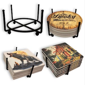 May include: Set of four black metal coaster holders with a variety of designs. The coasters feature images of a wolf howling at the moon, a cityscape, and a vintage moonshine label.