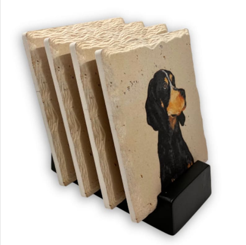 May include: Set of four square coasters with a black dog portrait. The coasters have a textured, light beige surface and are held in a black holder. The dog has black fur with tan and white markings.
