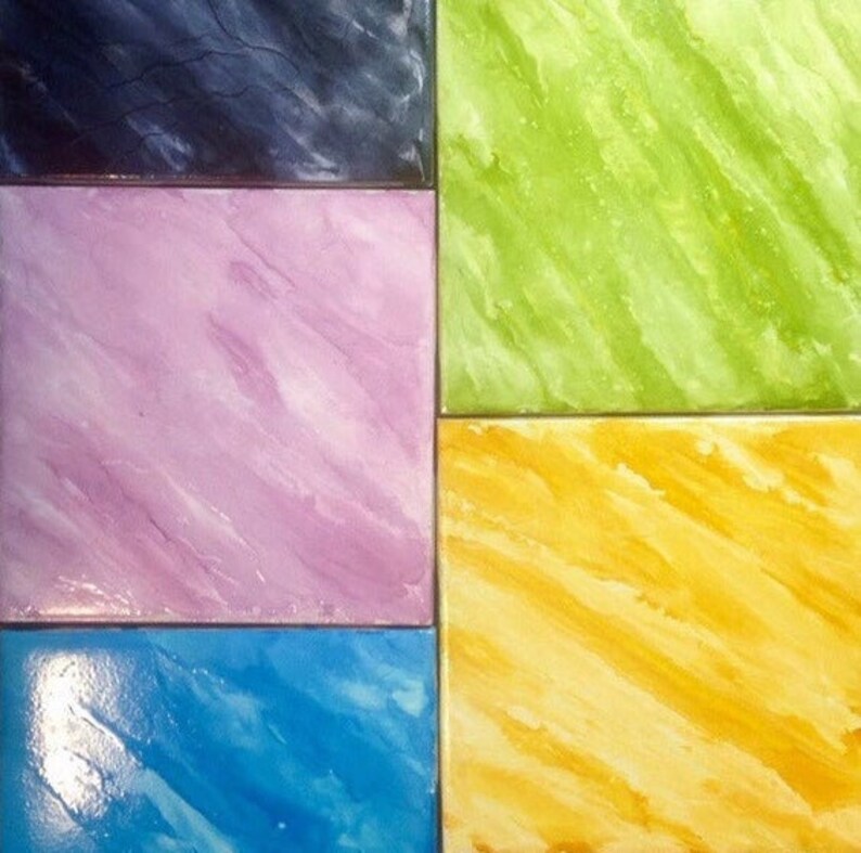 May include: A close-up of four square tiles with different marbled patterns. The tiles are painted in shades of blue, green, yellow, and pink.