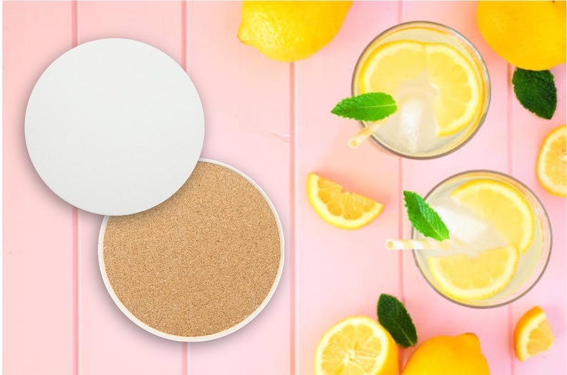 May include: Two white coasters, one with a cork surface and the other blank, on a pink background with lemons and glasses of lemonade.