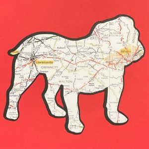 May include: A black and white outline of a bulldog, filled in with a map of Georgia. The map includes cities like Athens, Lawrenceville, and Jackson.