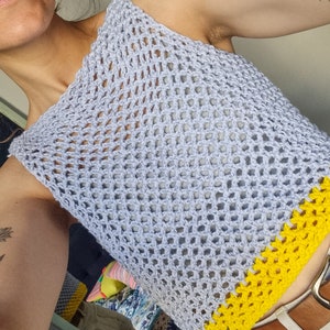 May include: A light blue crochet top with a yellow crocheted trim. The top is sleeveless and has a loose fit.