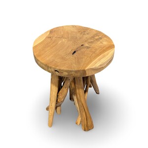 May include: A round side table crafted from natural light brown wood, featuring a smooth circular top with visible grain patterns and a base constructed from multiple interlocking, irregular wooden branches that serve as sturdy support legs.