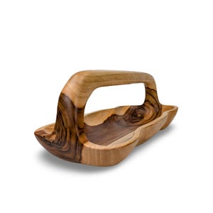 May include: A wooden serving tray with a carved handle. The tray is made of light and dark wood, giving it a natural, rustic look.