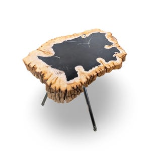 May include: A side table featuring a natural, irregular live-edge wood slab top with a smooth, polished black resin inlay in the center. The table is supported by three thin, dark metal legs that extend outward from the base of the wood slab.