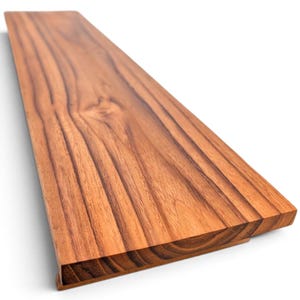 May include: A rectangular wooden shelf board featuring a warm, reddish-brown tone with prominent, dark brown linear grain patterns running along its length. The board has a smooth, flat surface and a clean, straight edge profile on all visible sides.