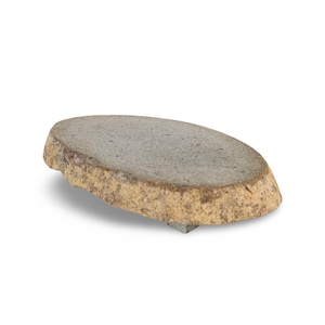 May include: A natural stone serving board with a rough, textured edge. The board is oval-shaped and has a gray surface with a tan-colored edge. It is elevated slightly by a small, gray support underneath.