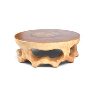 May include: A round wooden coffee table featuring a smooth, dark brown polished top surface with a visible natural wood grain and a light-colored, organic, carved base with multiple arched openings and a textured, uneven exterior finish.