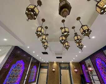 Könnte beinhalten: Eine weiße Decke mit mehreren verzierten, goldfarbenen Hängelampen mit filigranen Designs. Die Lampen sind symmetrisch angeordnet. Die Decke ist mit einem weißen und goldenen Muster verziert.