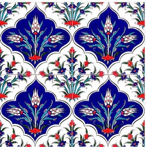 Puede incluir: Un azulejo de cerámica blanco con un patrón floral azul y blanco. El patrón presenta tulipanes estilizados con acentos rojos y hojas verdes. El azulejo está decorado con un diseño turco tradicional.