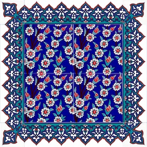 Puede incluir: Un azulejo de cerámica azul y blanco con un patrón floral. El azulejo tiene un borde decorativo con diseños intrincados. El patrón floral presenta flores blancas y capullos rojos sobre un fondo azul.