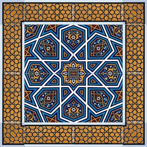 Puede incluir: Un azulejo decorativo con un patrón geométrico en tonos de azul, blanco, marrón y dorado. El azulejo presenta una estrella central rodeada de diseños intrincados.
