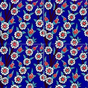 Puede incluir: Un azulejo azul y blanco con un patrón repetitivo de flores blancas con centros rojos sobre un fondo azul oscuro.