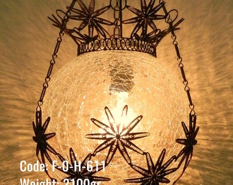 May include: A hanging light fixture with a clear, cracked glass globe and a metal frame with star-shaped designs. The fixture is suspended by a chain and has a tassel at the bottom. Code: F-O-H-611. Weight: 2100 grams. Height: 65 cm. Width: 27 cm. Depth: 27 cm.