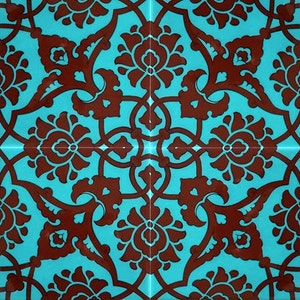 Puede incluir: Un azulejo cuadrado con un patrón repetitivo de diseños florales marrones sobre un fondo turquesa.