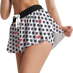 May include: White shorts with a black waistband and a drawstring. The shorts are patterned with black spade symbols and red hearts. The text "BBC" is inside the red hearts. The shorts have a flared skirt-like overlay.